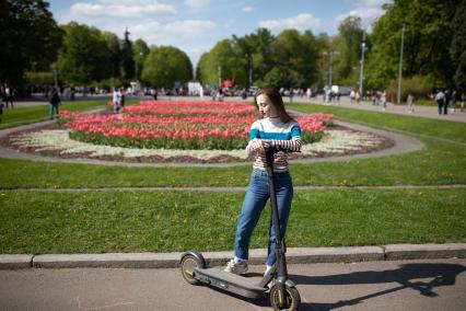 Москва. Девушка на самокате в парке.