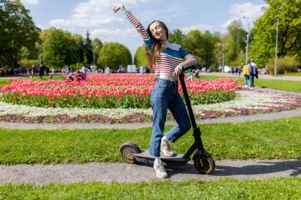 Москва. Девушка на самокате в парке.