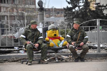 Донецкая область. г.Мариуполь. Военнослужащие ДНР сидят вместе с игрушечным медведем на улице.