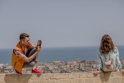 Дагестан, Дербент. Молодой человек фотографирует девушку на мобильный телефон.