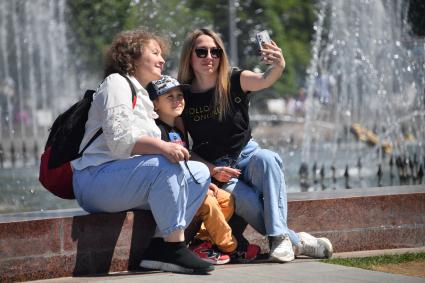 Москва.  Женщины фотографируются у фонтана на   ВДНХ.