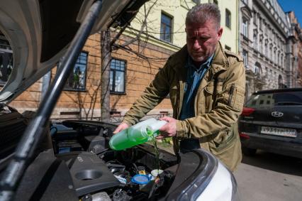 Санкт-Петербург. Мужчина доливает стеклоомывающую жидкость в автомобиль.