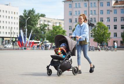 Пермь. Женщина с ребенком в детской коляске гуляют по улице.