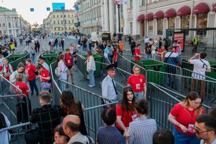 Санкт-Петербург.  Молодые люди проходят через ограждения во время  праздника выпускников `Алые паруса`.