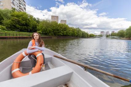 Москва.  Девушка катается в лодке на прудах в   Черкизовском детском парке.