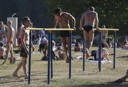 Москва.  Мужчины занимаются на брусьях на пляже.