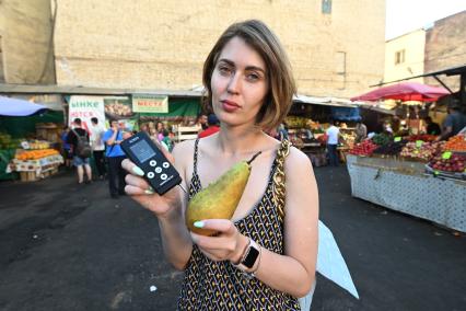 Санкт-Петербург.  Девушка измеряет количество нитратов в груше на Сенном рынке.