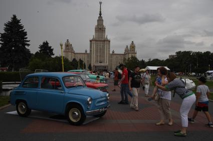Москва. Женщина фотографирует ретроавтомобиль на Воробьевых горах во время фестиваля `Ретрорейс` в рамках празднования Дня московского транспорта.