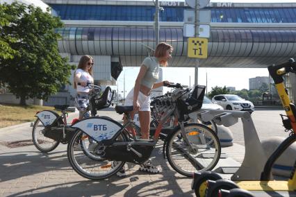 Москва. Девушка берет велосипед в городском общественном  прокате велосипедов.