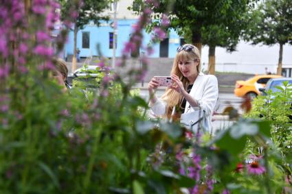 Москва. Женщина   фотографирует цветы во время фестиваля \"Цветочный джем: тропическое лето\"