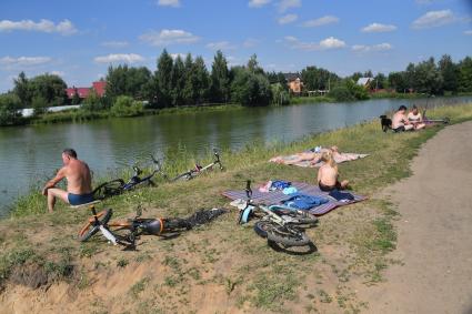 Москва.   Люди загорают на берегу озера в подмосковье.