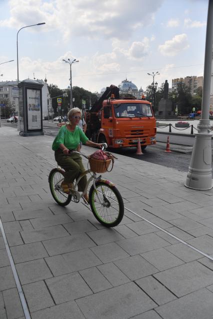 Москва.  Женщина едет на велосипеде.