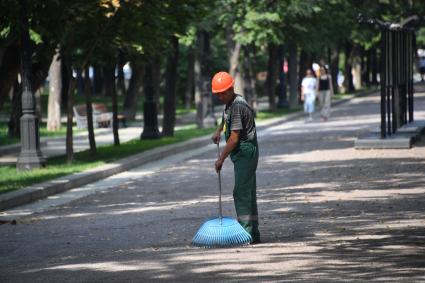 Москва.  Сотрудник коммунальных служб подметает дорожки на бульваре.