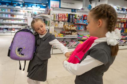 Санкт-Петербург. Девочки выбирают рюкзаки в отделе школьных принадлежностей в магазине канцтоваров перед началом учебного года.