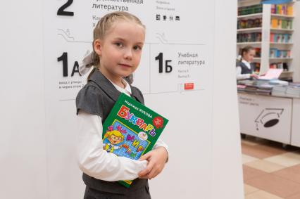 Санкт-Петербург. Девочка с букварем в отделе школьных принадлежностей в магазине перед началом учебного года.