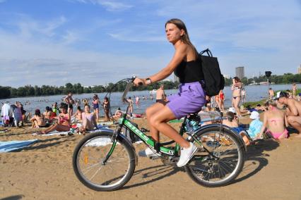 Москва. Девушка едет на велосипеде по пляжу в Косино.