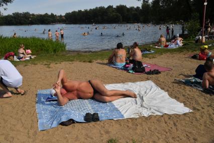 Москва. Мужчина загорает на пляже Косинского озера.