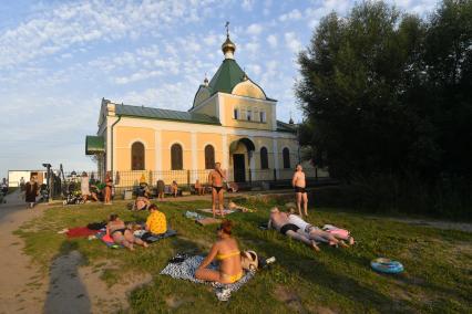 Москва. Природно-исторический парк `Косинский`. Люди загорают у храма Успения Пресвятой Богородицы у Святого озера.