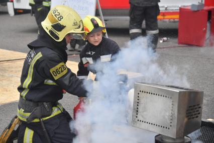 Москва. Мальчик вмести с пожарным тушат огонь в рамках III Международного пожарно-спасательного конгресса на территории Парка Горького.