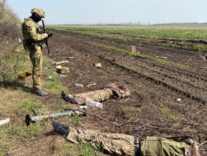 Харьковская область. Российский военнослужащий изучает документы убитых украинских солдат.