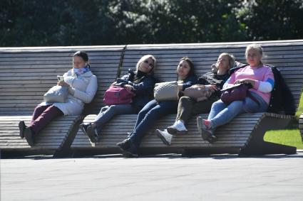 Москва. Посетители на скамейке на ВДНХ во время празднования Дня города.