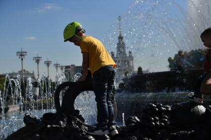 Москва. Мальчик играет у фонтана  `Каменный цветок` на ВДНХ во время празднования Дня города.