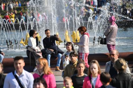 Москва.  Люди гуляют у фонтана   `Дружба народов` на ВДНХ во время празднования Дня города.