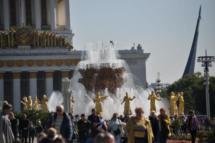 Москва.  Люди гуляют у фонтана   `Дружба народов` на ВДНХ во время празднования Дня города.