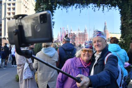 Москва. Мужчина и женщина фотографируются  на праздничных мероприятиях в честь Дня города на Тверской улице.