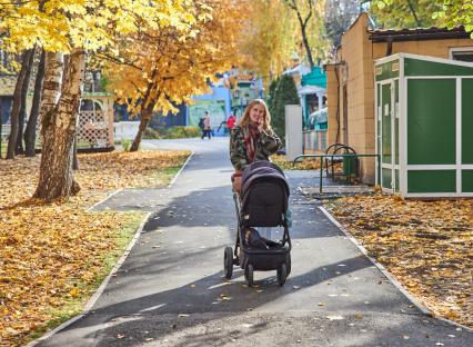 Пермь. Девушка гуляет с детской коляской в осеннем парке