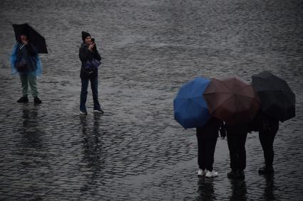 Москва.  Прохожие на Красной площади во время дождя.