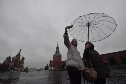 Москва.  Прохожие на Красной площади во время дождя.