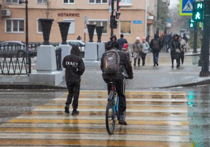 Пермь. Велосипедист переезжает дорогу по пешеходному переходу.