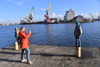 Калининград. Женщтна фотографирует мальчика на городской набережной.