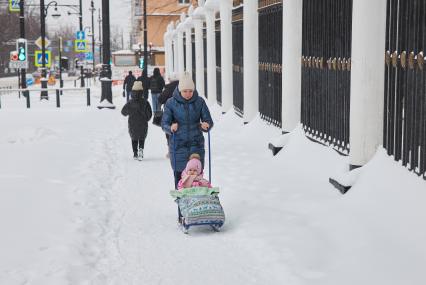 Пермь. Женщина везет ребенка на санках.