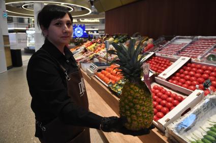 Москва. Продавщица демонстрирует ананас на территории нового пространства `Депо. Три вокзала`на Новорязанской улице.
