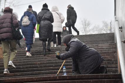 Москва. Пожилая женщина просит милостыню у подземного перехода.