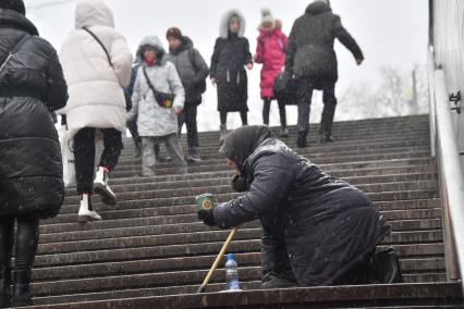 Москва. Пожилая женщина просит милостыню у подземного перехода.