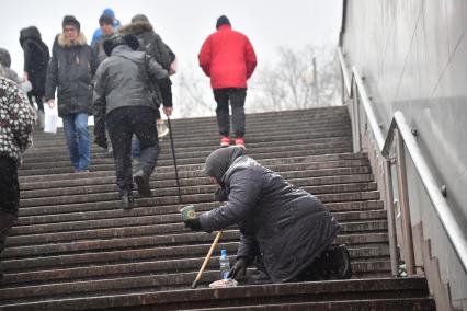 Москва. Пожилая женщина просит милостыню у подземного перехода.