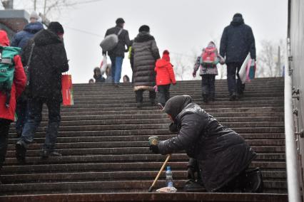 Москва. Пожилая женщина просит милостыню у подземного перехода.