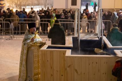 Красноярск. Священнослужитель освящает воду в иордани во время празднования Крещения .