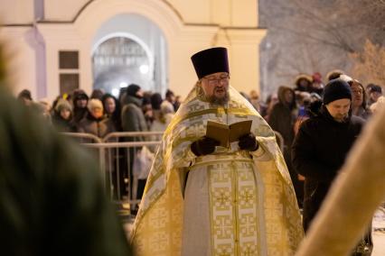 Красноярск. Священнослужитель освящает воду в иордани во время празднования Крещения .