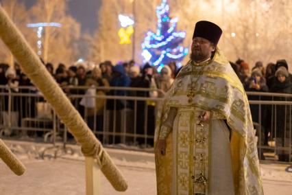 Красноярск. Священнослужитель освящает воду в иордани во время празднования Крещения .