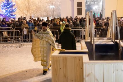 Красноярск. Священнослужитель освящает воду в иордани во время празднования Крещения .