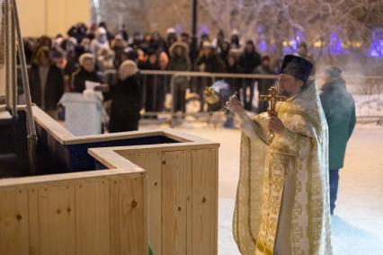 Красноярск. Священнослужитель освящает воду в иордани во время празднования Крещения .