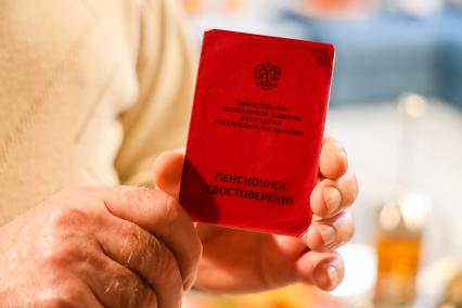 Красноярск. Пожилой мужчина показывает свое пенсионное удостоверение.
