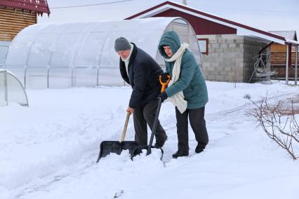 Красноярск. Пожилая пара убирает снег на своем приусадебном участке.