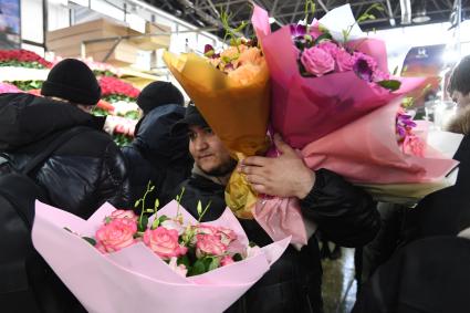 Москва. Мужчина с букетами цветов на Рижском цветочном рынке в преддверии праздника 8 Марта.