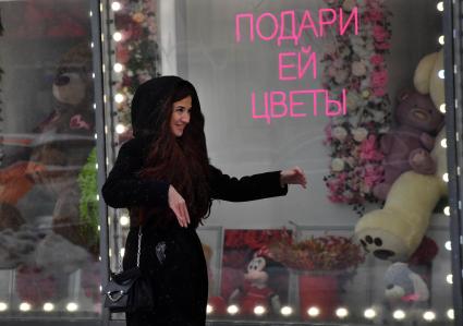 Москва. Девушка у  витрины магазина  в международный женский день 8 Марта.