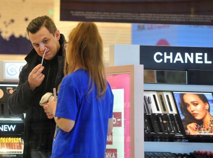 Москва.  Мужчина выбирает духи в магазине в международный женский день 8 Марта.